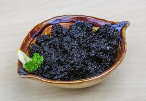 Black caviar in a bowl on wooden background photo