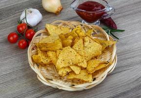 nachos en una canasta sobre fondo de madera foto