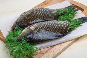 Two crucian on wooden board and wooden background photo