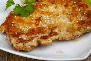 Pork schnitzel on the plate and wooden background photo