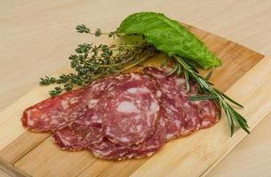 Salami on wooden board and wooden background photo