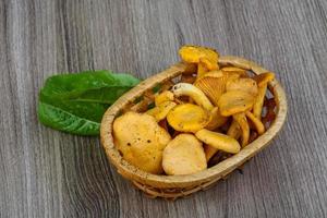 Chanterelle in a basket on wooden background photo