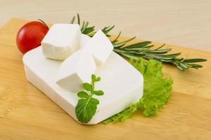 Feta cheese on wooden board and wooden background photo