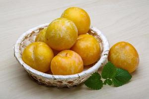 Yellow plums in a basket on wooden background photo