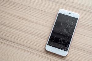 broken glass of mobile phone screen on wooden background photo