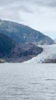 Panning view of ice and snow covered mountains surrounded by water and fog video