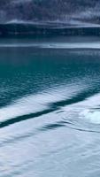 Fog floats above the mountain lake and shore line as seen from boat video