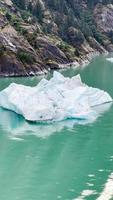 Iceberg dans l'eau verte glacée de l'Alaska avec des montagnes en arrière-plan video