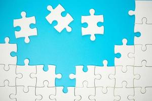 White part of jigsaw puzzle pieces on blue background. concepts of problem solving, business success, teamwork, Team playing jigsaw game incomplete, Texture photo with copy space for text