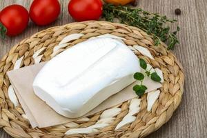 Feta cheese on wooden board and wooden background photo