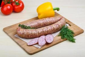 Smoked sausages on wooden board and white background photo