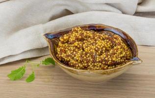 French mustard in a bowl on wooden background photo