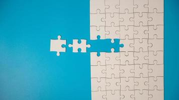 White part of jigsaw puzzle pieces on blue background. concepts of problem solving, business success, teamwork, Team playing jigsaw game incomplete, Texture photo with copy space for text