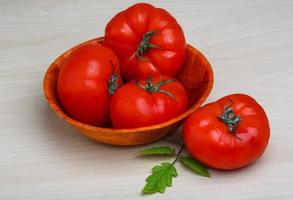 Red tomatoes in a bowl on wooden background photo