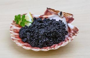Black caviar on the plate and wooden background photo