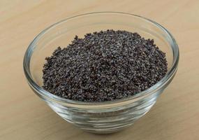 Poppy seeds in a bowl on wooden background photo