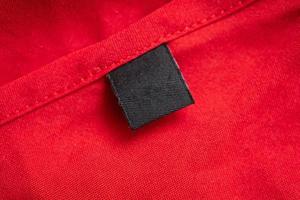 Blank black laundry care clothing label on red color fabric texture photo