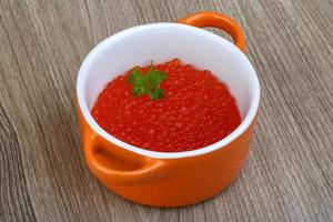 Red caviar in a bowl on wooden background photo