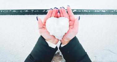 Top down view woman in two hands hold ice heart made of snow. Girl give heart on valentines day photo