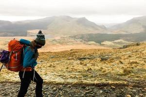 las mujeres excursionistas suben la montaña en un clima frío y brumoso por la mañana. paisaje de senderos para caminatas a snowdon. montañeros escalando montañas en hermosos paisajes naturales, actividad deportiva foto