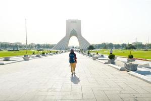 teherán, irán, 2022 - mujer mochilera camina por la torre azadi - famoso punto de referencia en teherán en la capital de irán. derechos de la mujer y turismo en oriente medio foto