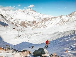 Group of male skiers ski downhill in Kobi off-piste in Gudauri ski resort, caucasus mountains. Freeride in sunny day in winter season for fun and extreme photo