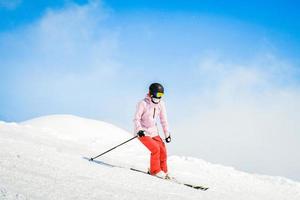 Young woman skier ski ride downhill in scenic caucasus mountains in fast freeze motion steep downhill solo photo