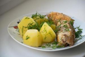 Slices of grilled sea bass with boiled potatoes on the plate. photo