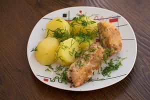 Slices of grilled sea bass with boiled potatoes on the plate. photo