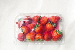 Sweet fresh strawberries in plastic container on the table. Supermarket shop plastic box container with red fruits. photo