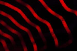 Desenfoque rojo abstracto efectos de luz bokeh en la textura de fondo negro de la noche foto