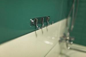 Chrome hook for towel in bathroom. a metal hanger with many hooks for towels and clothes in the bathroom. Shallow depth of field. House, quarter, apartment or hotel. selective focus photo