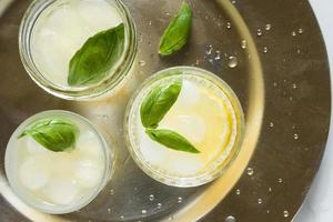 Freshly Squeezed Lemonade Garnished with Basil Leaves Served on a Gold Tray photo