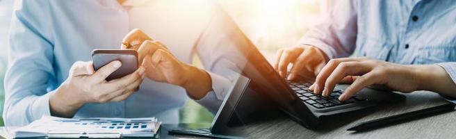 Businessman hands working with finances about cost and calculator and laptop with tablet, smartphone at office in morning light photo