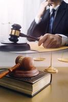 Justice and law concept.Male judge in a courtroom with the gavel, working with, computer and docking keyboard, eyeglasses, on table in morning light photo