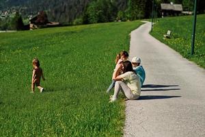 madre sentada con niños en el camino en la pradera alpina en untertauern, austria. foto