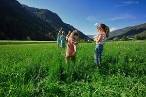 cuatro niños juegan en un prado alpino en untertauern, austria. foto