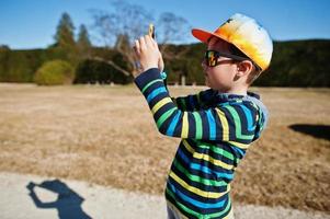 niño con gorra y gafas de sol haciendo fotos por teléfono en el parque lednice, república checa.