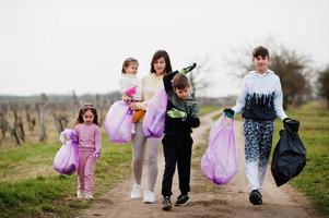 Family with trash bag collecting garbage while cleaning in the vineyards . Environmental conservation and ecology, recycling. photo