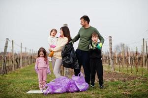 Family with trash bag collecting garbage while cleaning in the vineyards . Environmental conservation and ecology, recycling. photo