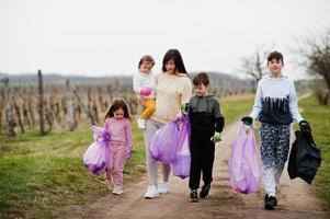 Family with trash bag collecting garbage while cleaning in the vineyards . Environmental conservation and ecology, recycling. photo