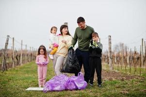 Family with trash bag collecting garbage while cleaning in the vineyards . Environmental conservation and ecology, recycling. photo
