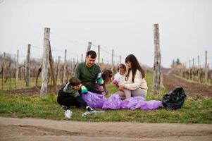 Family with trash bag collecting garbage while cleaning in the vineyards . Environmental conservation and ecology, recycling. photo