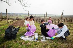 Family with trash bag collecting garbage while cleaning in the vineyards . Environmental conservation and ecology, recycling. photo