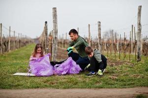 Family with trash bag collecting garbage while cleaning in the vineyards . Environmental conservation and ecology, recycling. photo