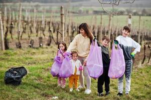 Family with trash bag collecting garbage while cleaning in the vineyards . Environmental conservation and ecology, recycling. photo