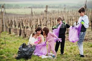 familia con bolsa de basura recogiendo basura mientras limpia en los viñedos. conservación ambiental y ecología, reciclaje. foto