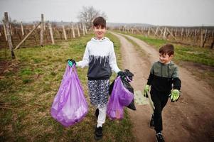 hermanos con bolsa de basura recogiendo basura mientras limpian en los viñedos. conservación ambiental y ecología, reciclaje. foto