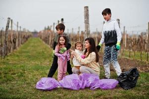 Family with trash bag collecting garbage while cleaning in the vineyards . Environmental conservation and ecology, recycling. photo