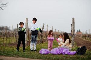 Family with trash bag collecting garbage while cleaning in the vineyards . Environmental conservation and ecology, recycling. photo
